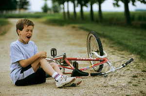 Little boy crying on a path, near his bike